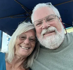man and woman smiling under a beach umbrella